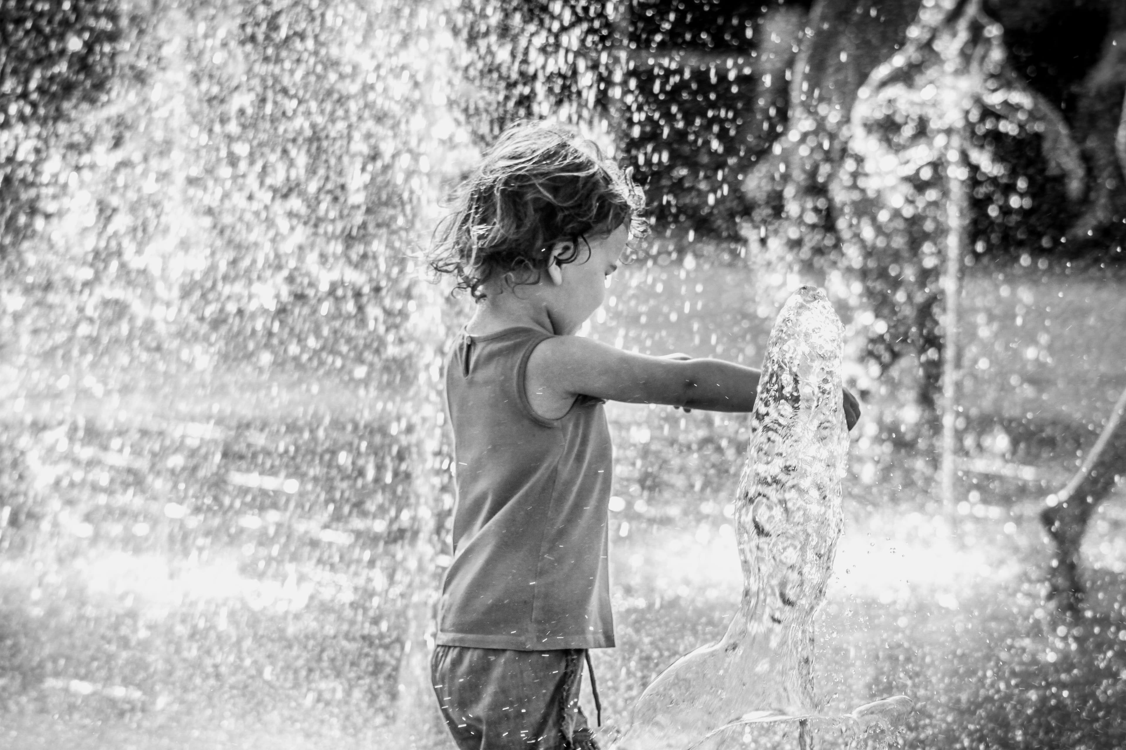Child standing among water jets at a splash pad