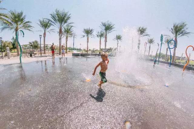 Kids playing at a Phoenix splash pad surrounded by palm trees