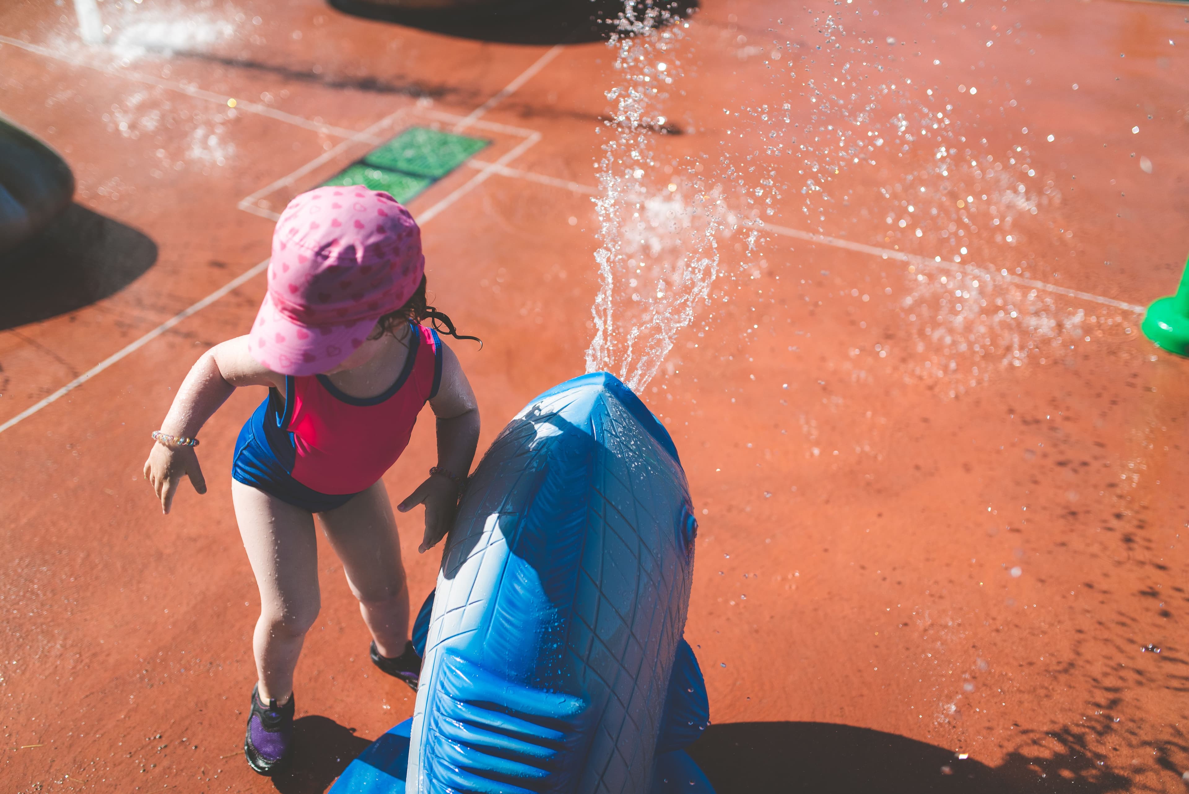 toddler in water shoes, playing at a public splash pad